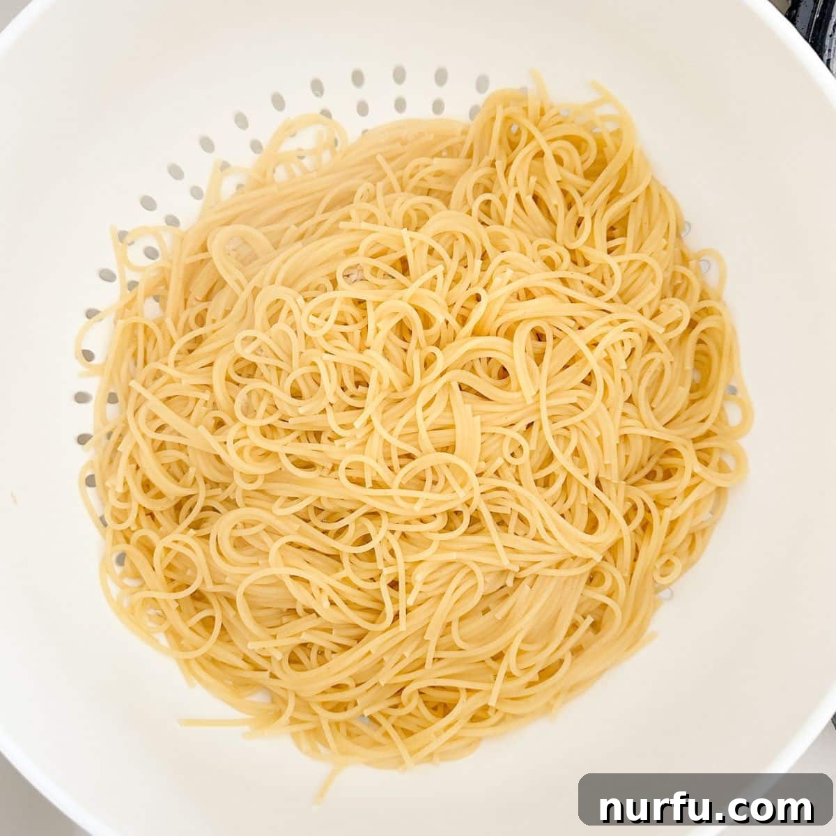 Zesty Spaghetti Salad 4 Colander with spaghetti noodles.