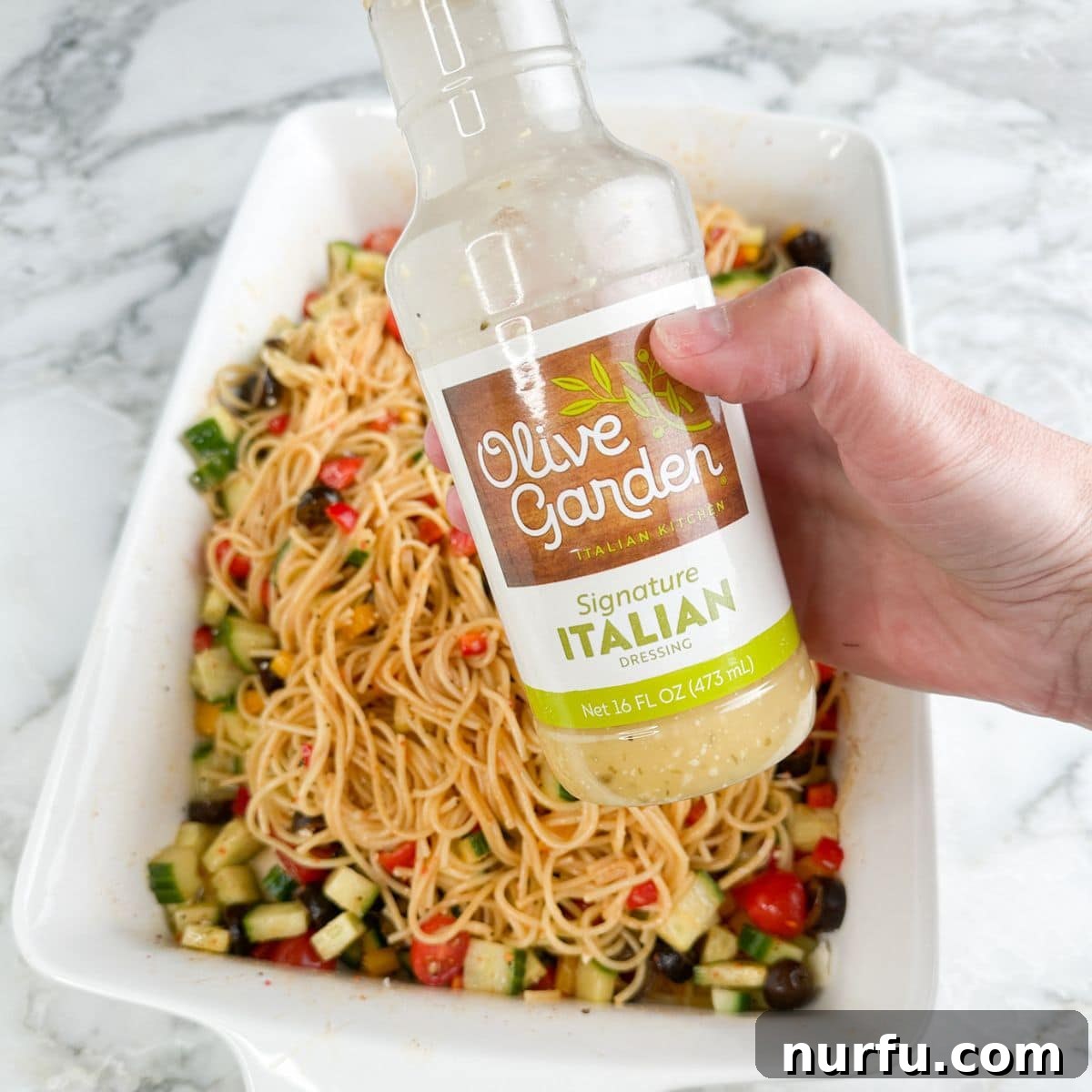 Zesty Spaghetti Salad 9 Hand holding a bottle of Italian dressing.