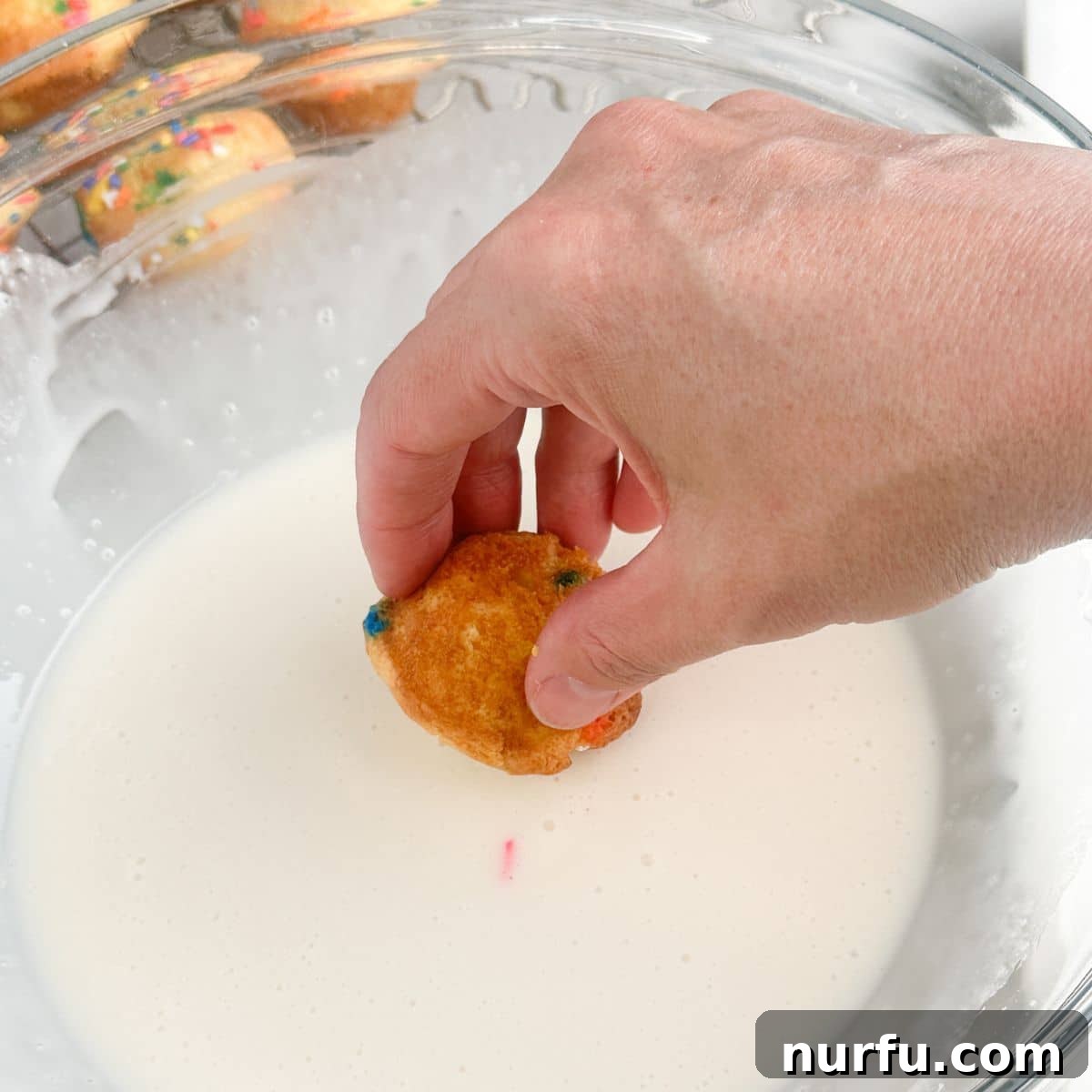 How to Make Sprinkle Blossoms: Cute Cake & Cookie Toppers 6 Bowl of icing with mini cake being dipped in.
