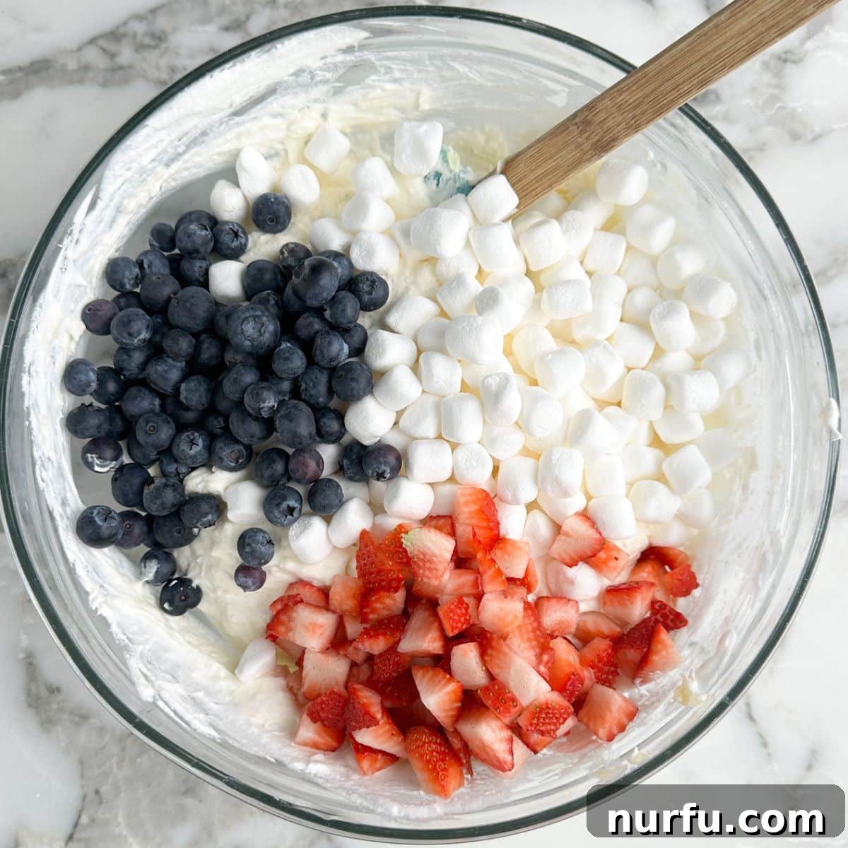 Patriotic Red, White & Blue Cheesecake Salad Recipe 5 Bowl with cream cheese, mini marshmallows, blueberries, and strawberries.