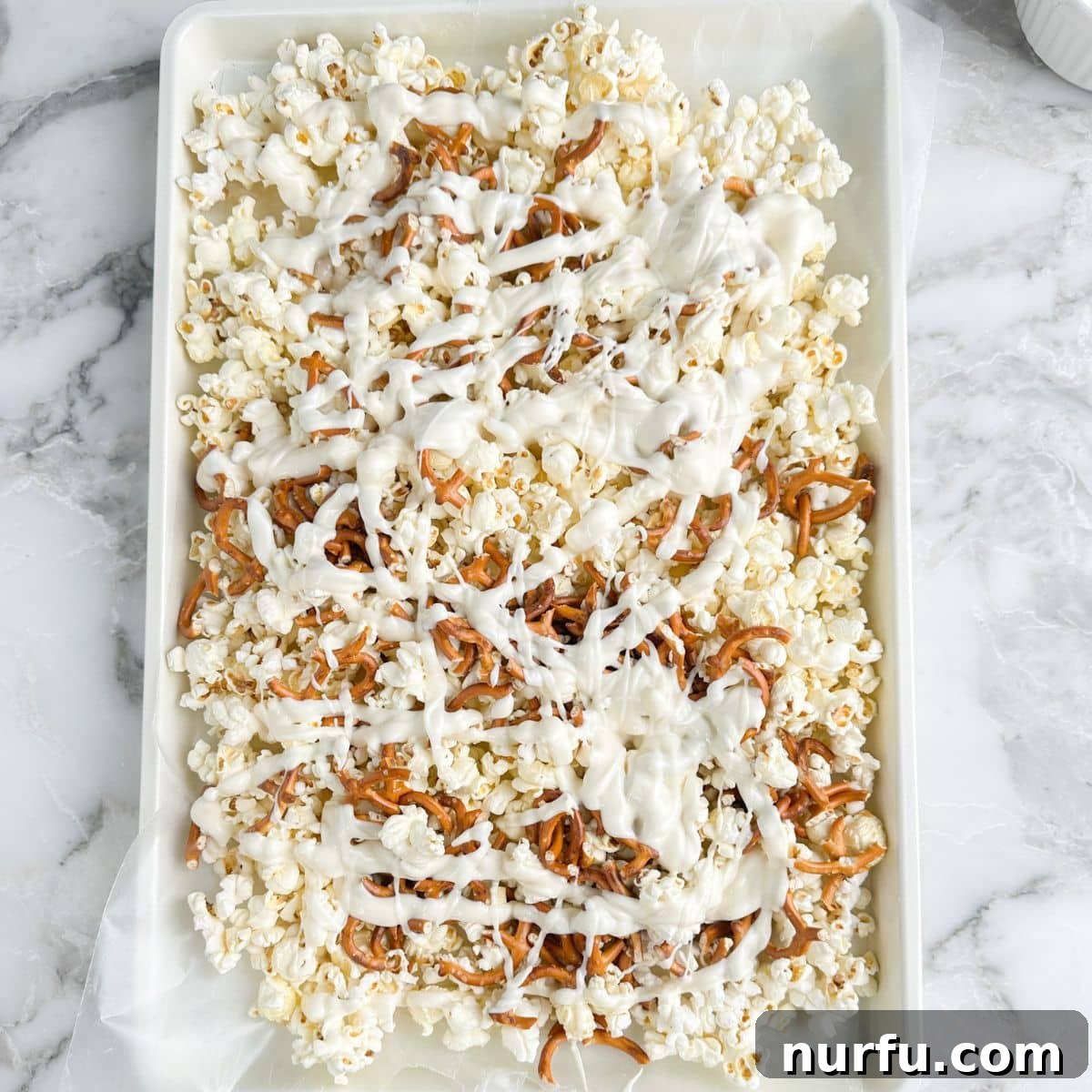 Patriotic Red, White & Blue Popcorn Snack Mix Recipe 4 Baking sheet with popcorn, pretzels, mini marshmallows, and melted white chocolate.