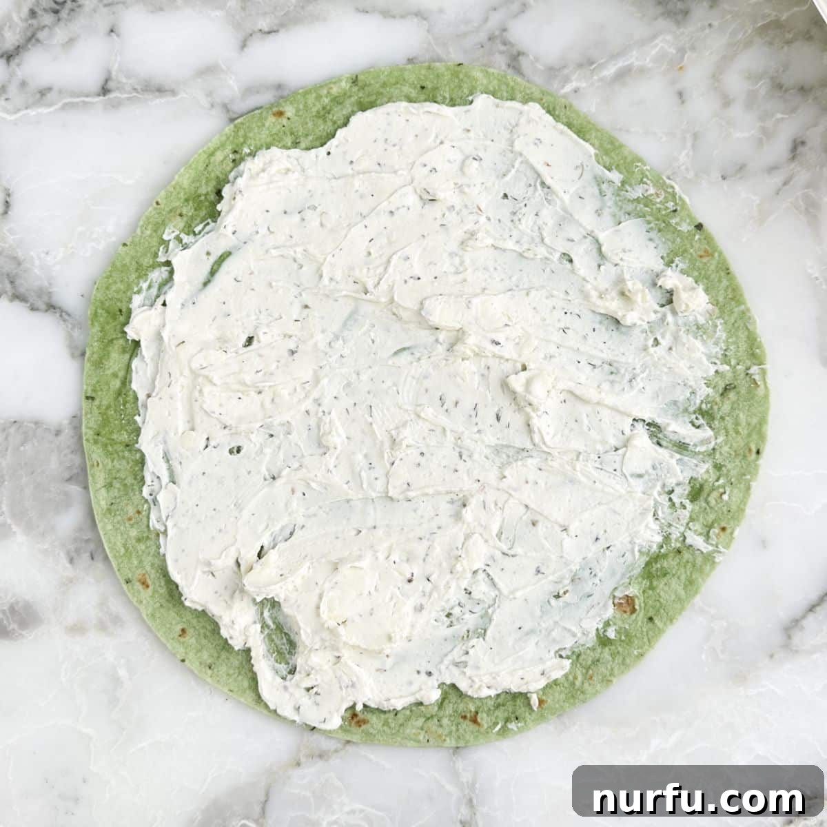 Greek Pinwheel Appetizers: Spinach, Feta & Olive Rolls 4 Green tortilla with cream cheese spread on top.