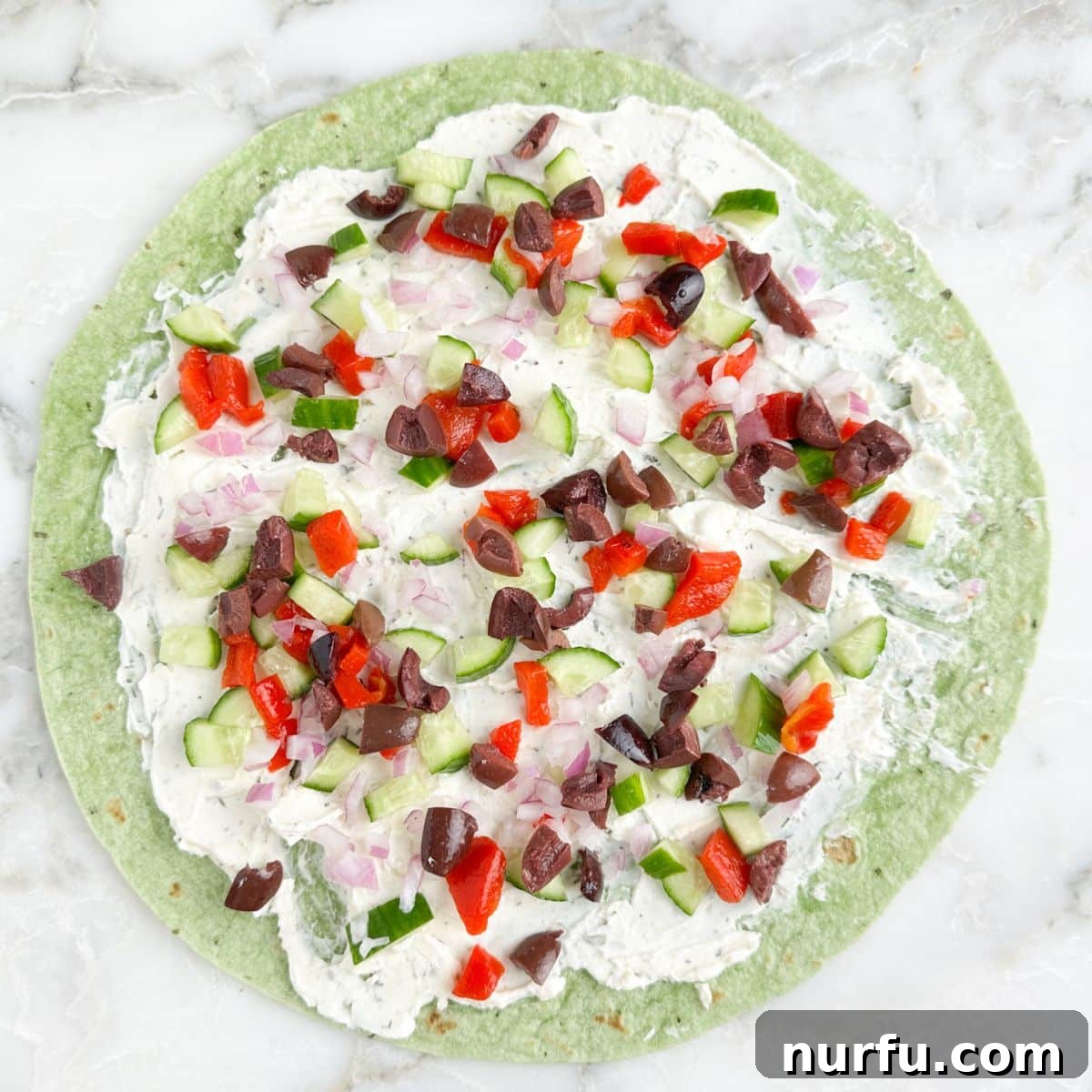 Greek Pinwheel Appetizers: Spinach, Feta & Olive Rolls 5 Green tortilla topped with cream cheese spread, cucumber, peppers, and olives.