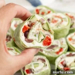 Greek Pinwheel Appetizers: Spinach, Feta & Olive Rolls 9 Hand holding Greek pinwheel.