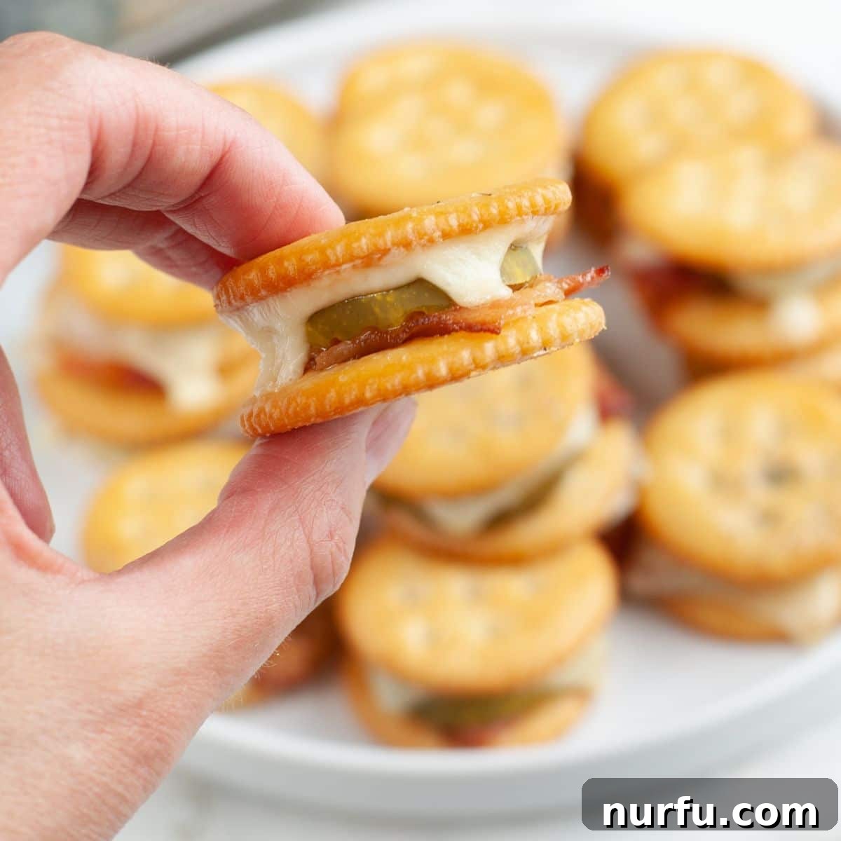 Ritz Crackers with Bacon and Pickle Spread: Crispy Party Snack 8 Hand holding Ritz cracker with bacon and pickle.