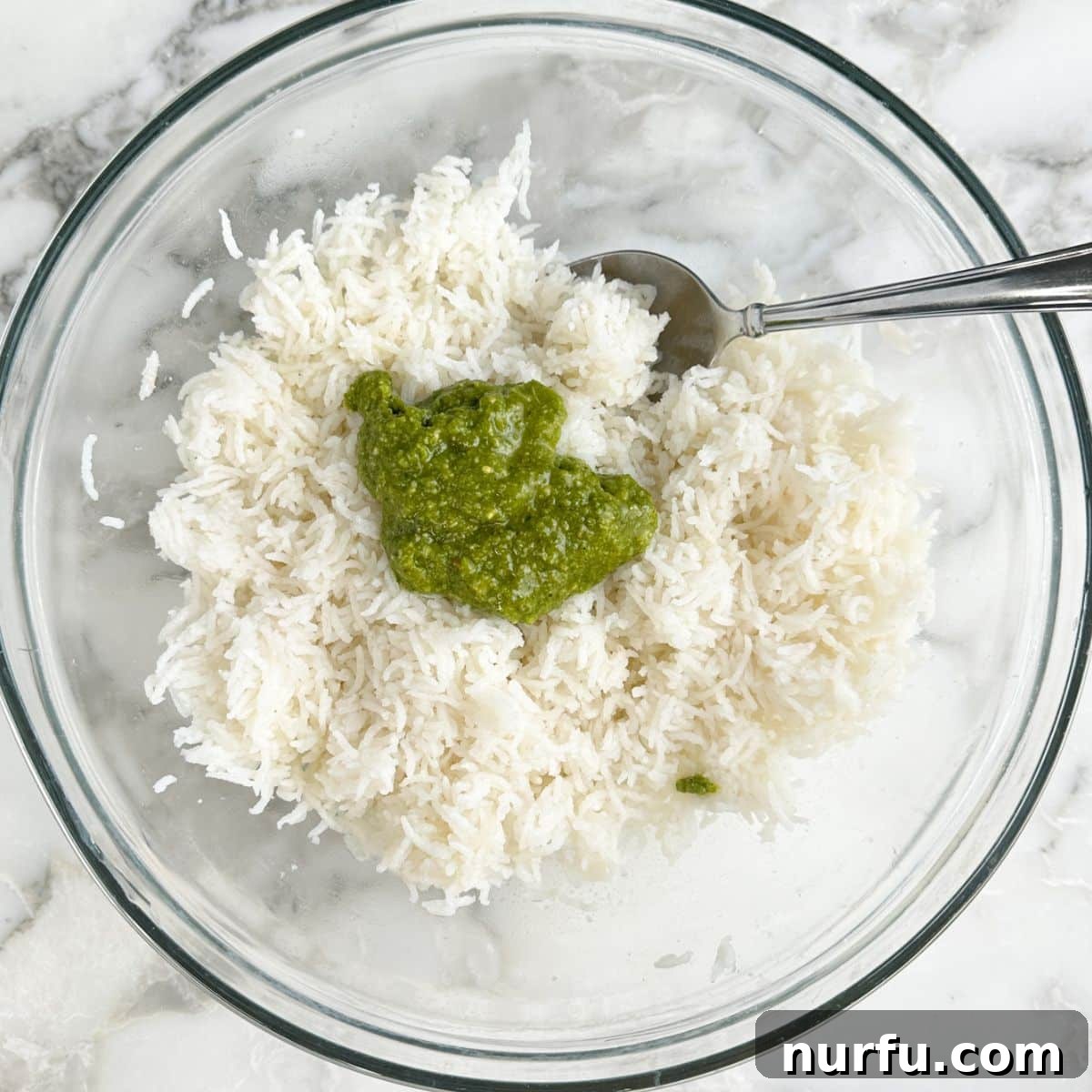 Bowl of basmati rice with pesto sauce and a spoon. 
