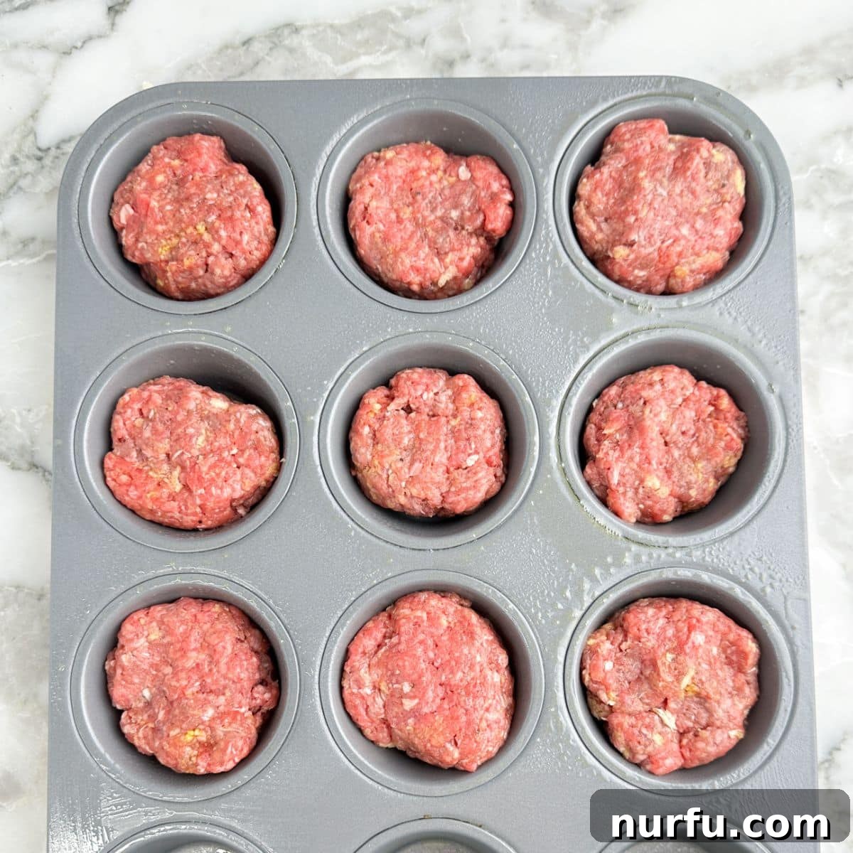 Mini Meatloaf Muffins Recipe with Cheesy Center 5 Muffin tin with unbaked meatloaf mixture.
