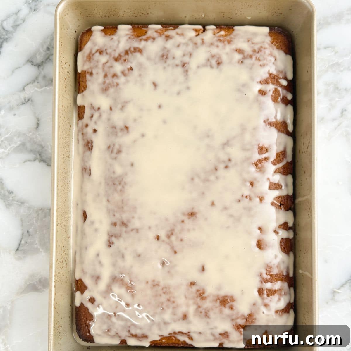 Baking pan with baked root beer cake topped with icing. 