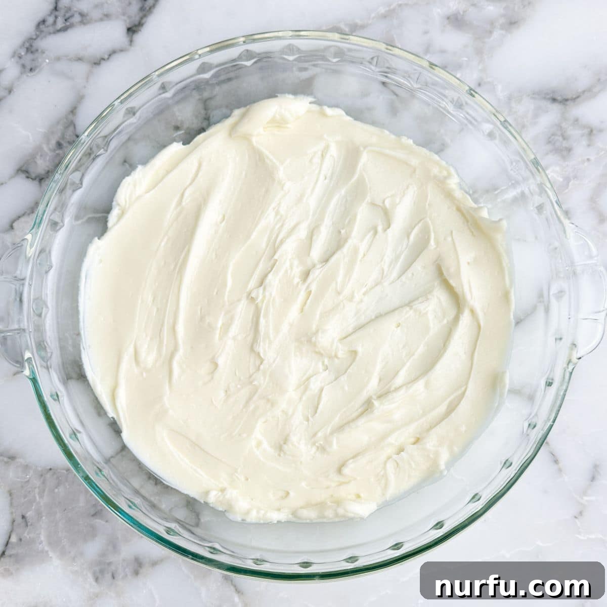 Pie dish with cream cheese spread out.