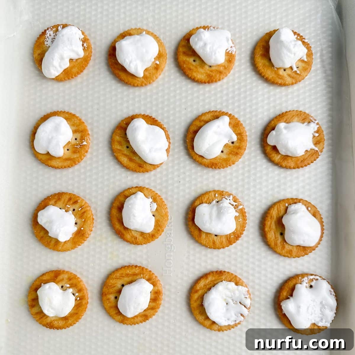 Ritz crackers topped with marshmallow creme on a cookie sheet. 