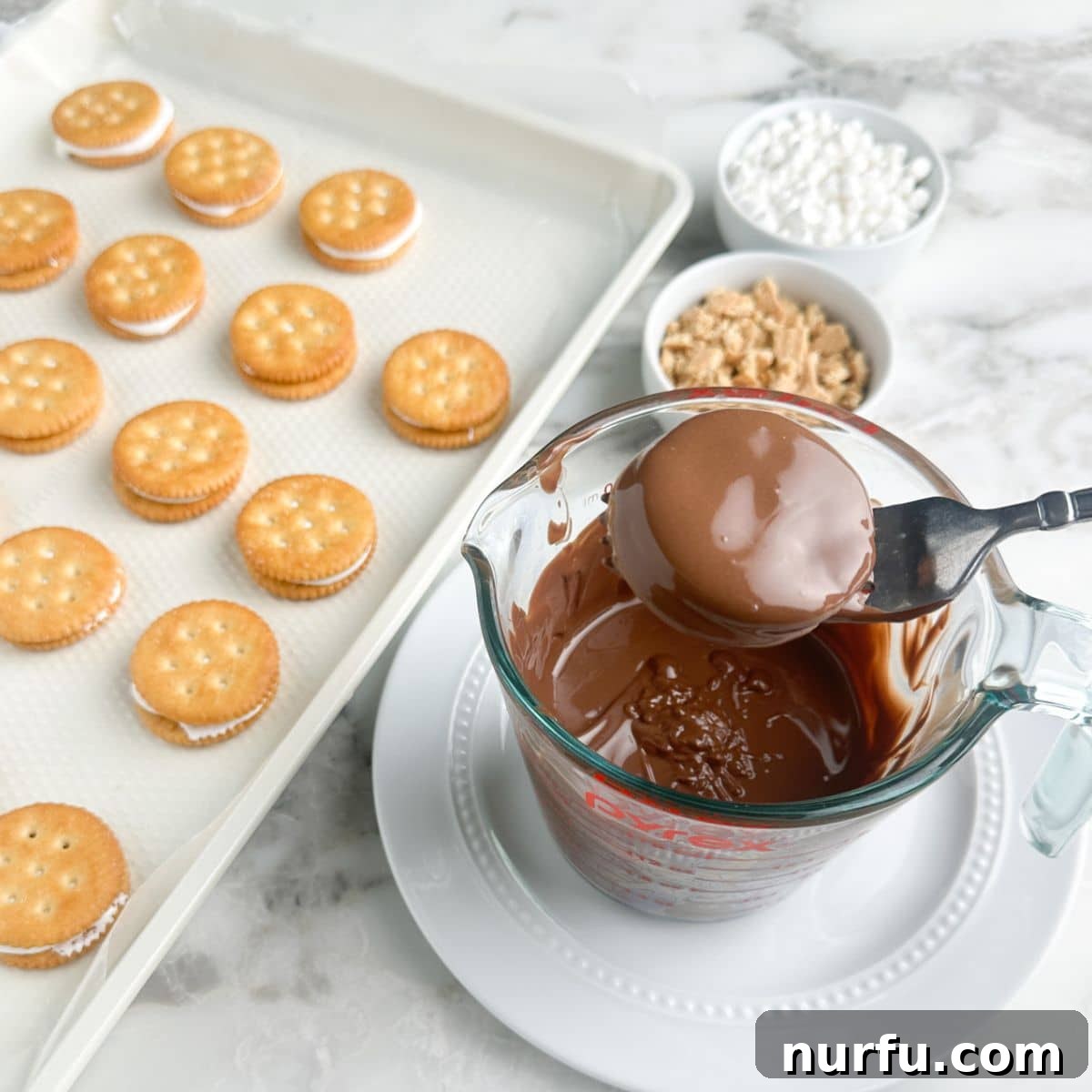 Fork with crackers dipped in melted chocolate. 