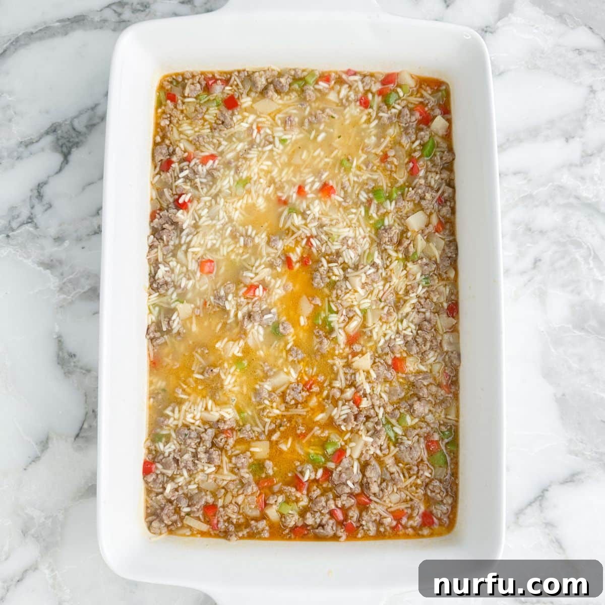 One-Pan Sausage and Rice Casserole 7 Casserole dish with unbaked sausage and rice casserole.