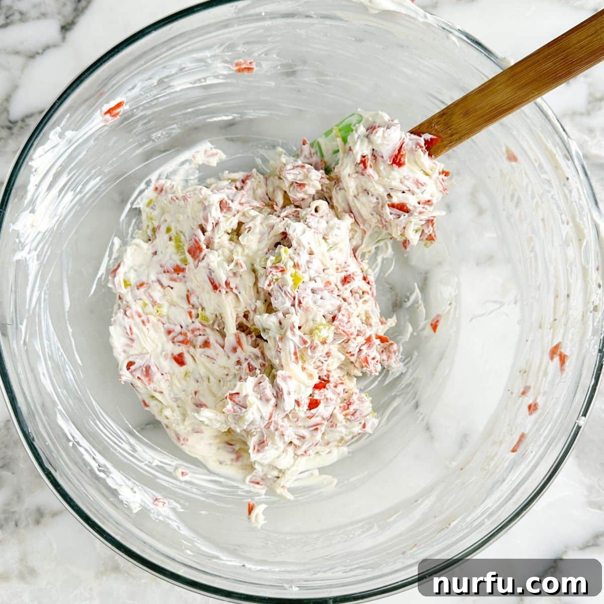 Bowl of mixed pepperoni dip with a spatula.
