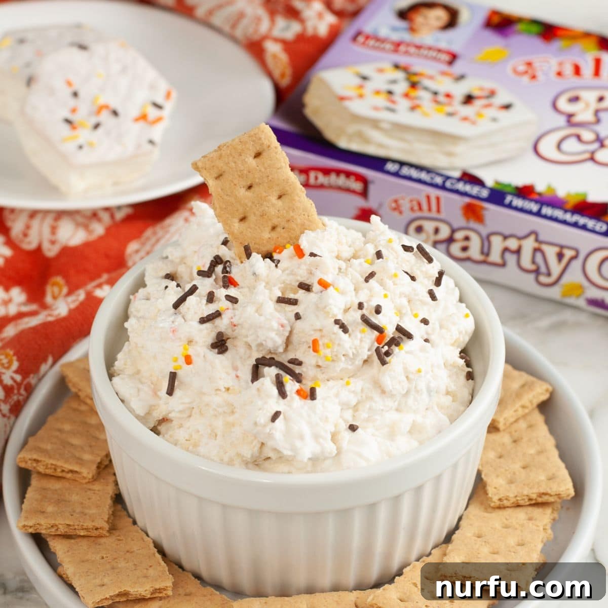 Bowl of Fall party cake dip with a graham cracker.