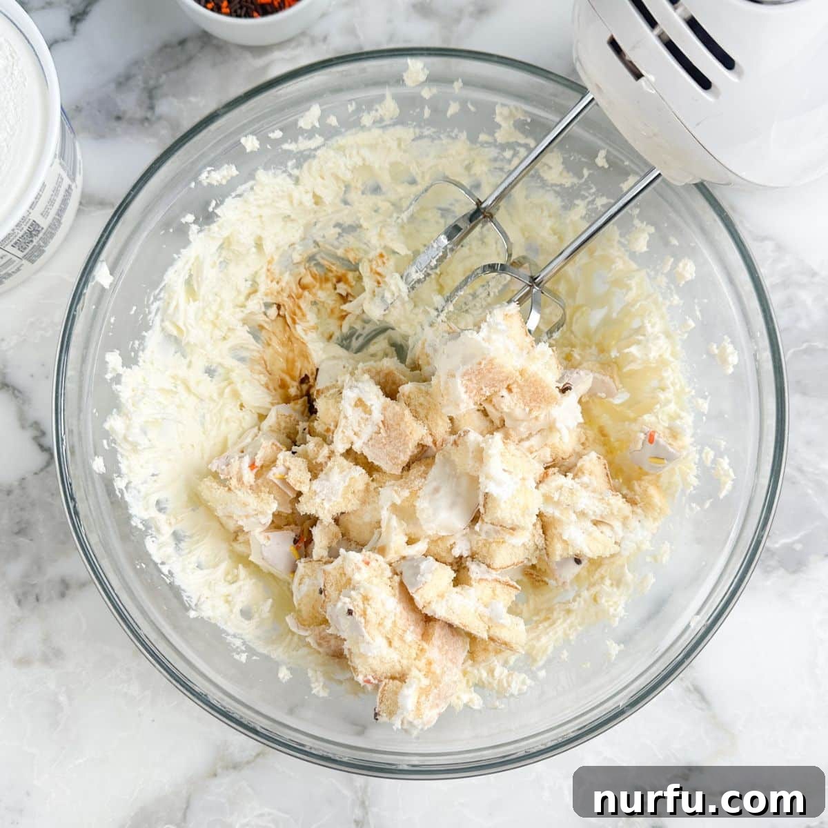 Bowl of whipped cream cheese and chopped up vanilla cake.